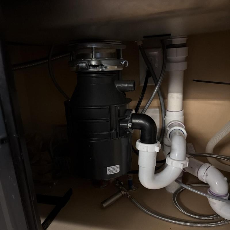 Garbage disposal unit with connected drain pipes under sink