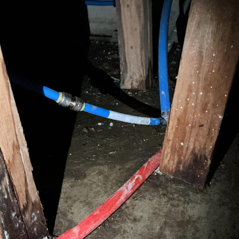 Blue PEX water pipe with metal fitting in crawl space