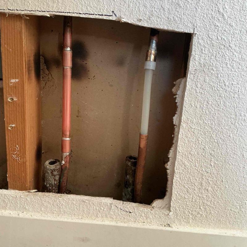 Manifold pipes cut, capped, and rerouted inside wall