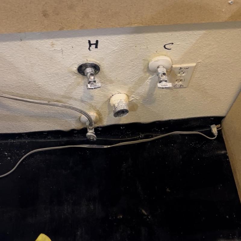 Water supply valves and drain pipe on kitchen wall