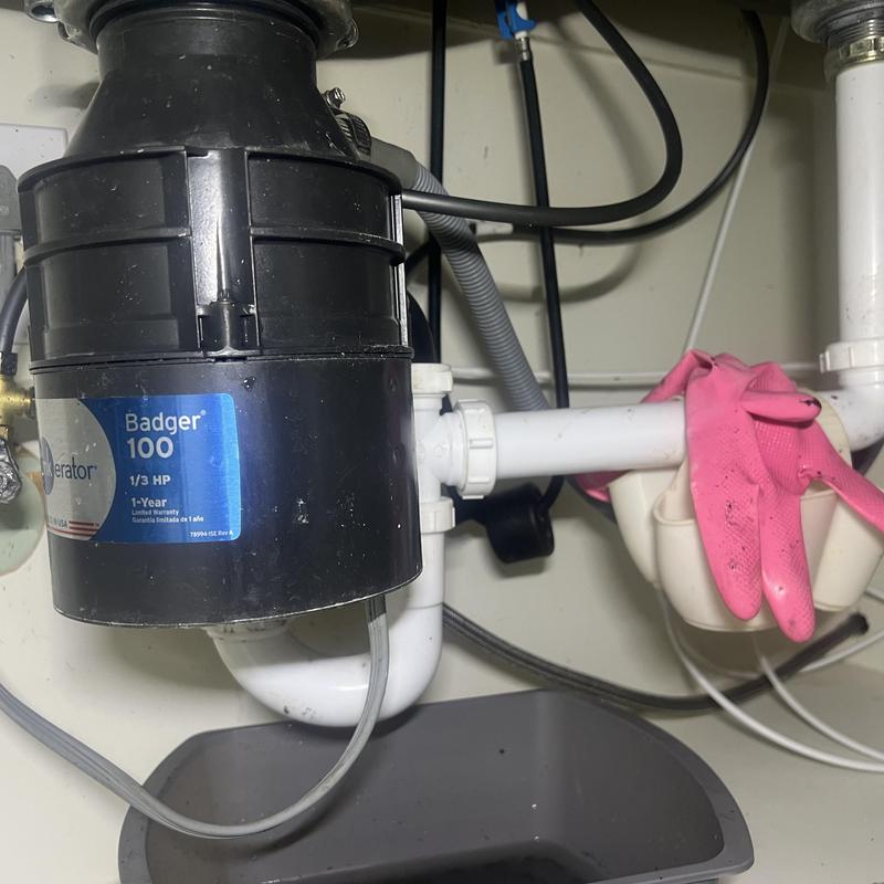 Garbage disposal and sink drain with pink gloves nearby
