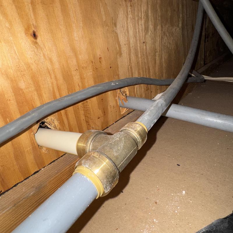 Water line with brass T-fitting in crawl space