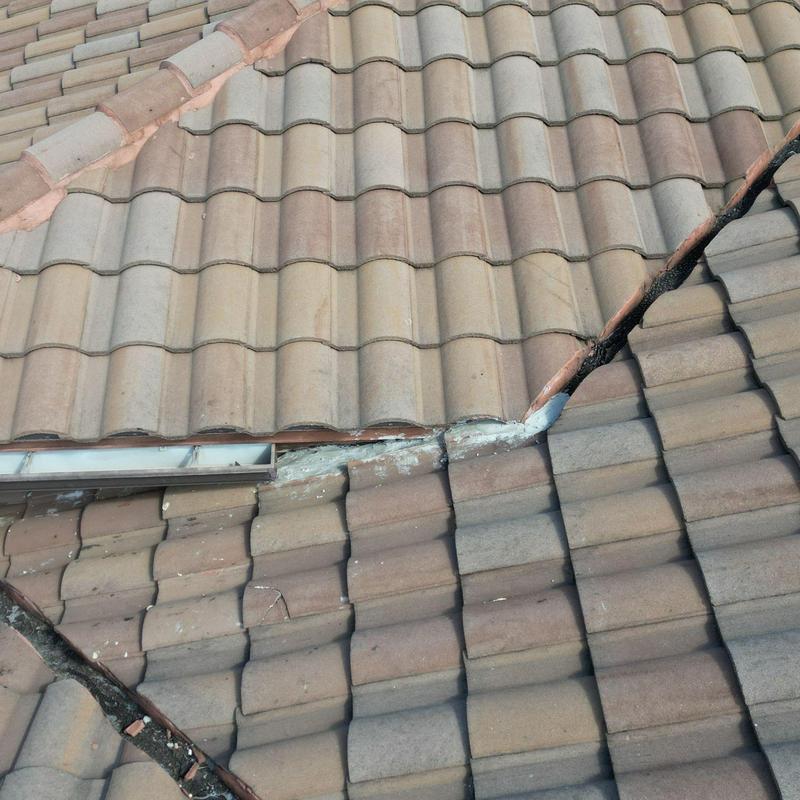 Tile roof with cracked and displaced tiles near valley