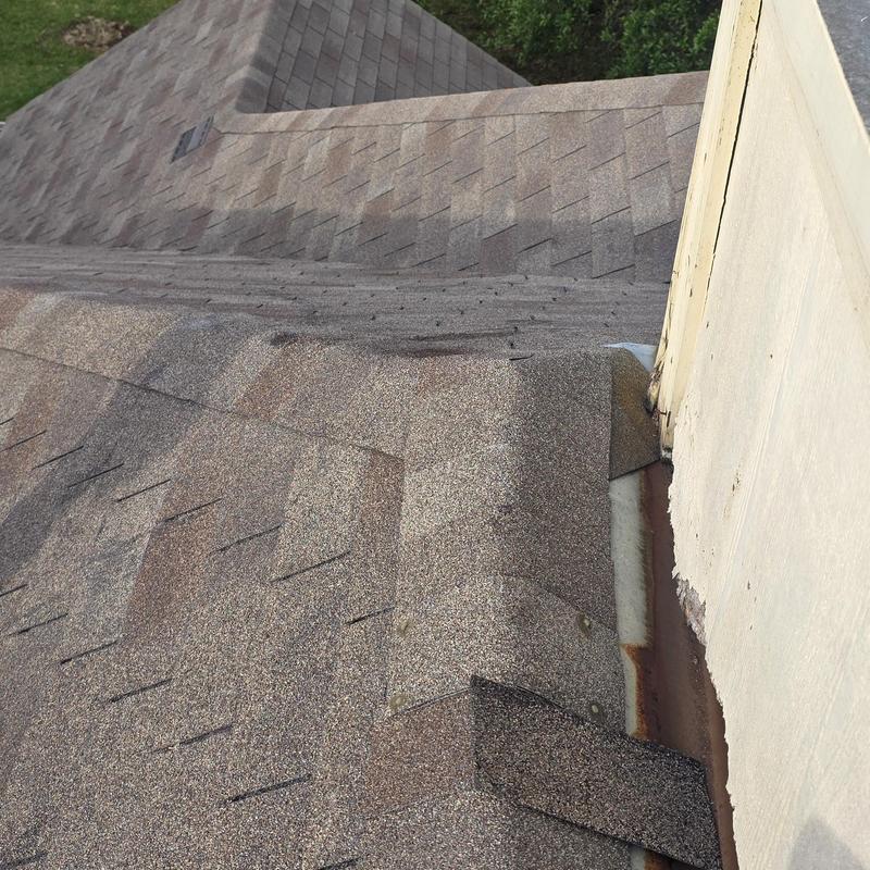 Asphalt shingle roof ridge with wind and hail damage