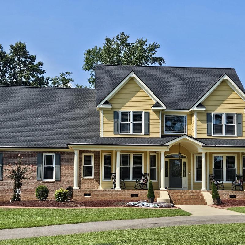 Asphalt shingle roof on yellow siding house