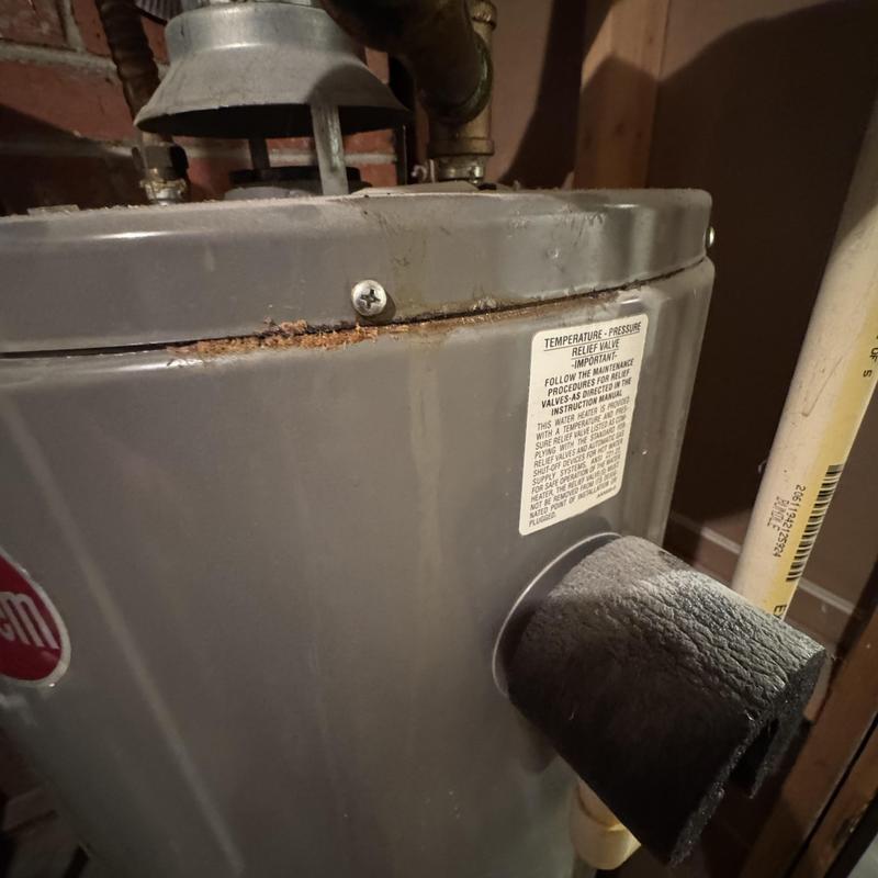 Water heater with rust and insulation on pipe in basement