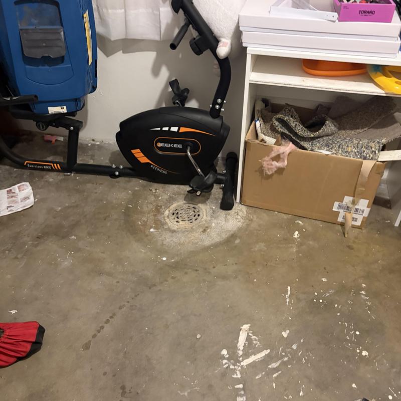 Floor drain with surrounding concrete and exercise bike nearby