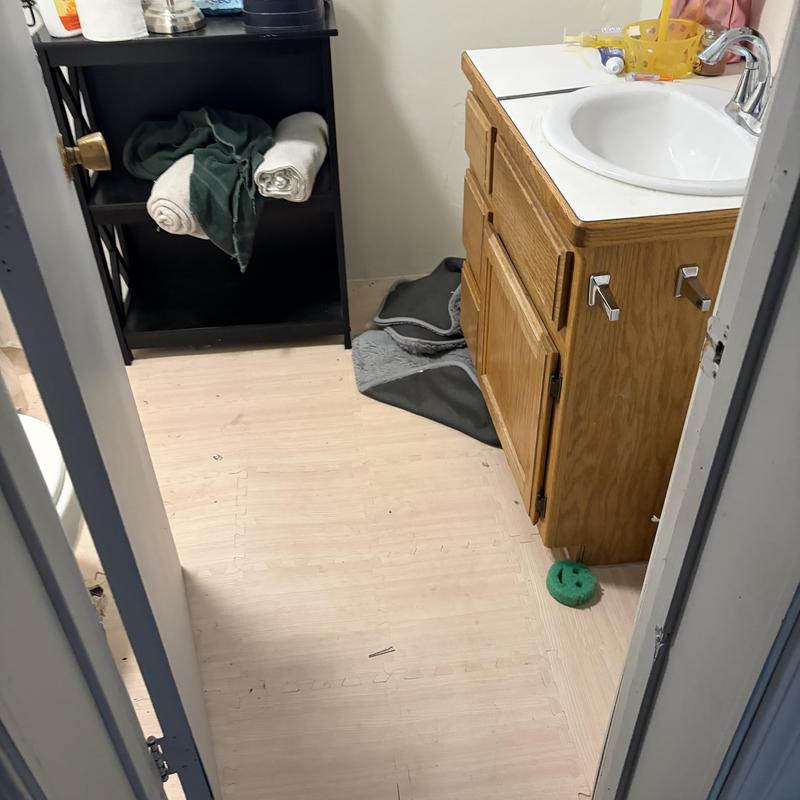 Bathroom sink and cabinet with towels and floor mats
