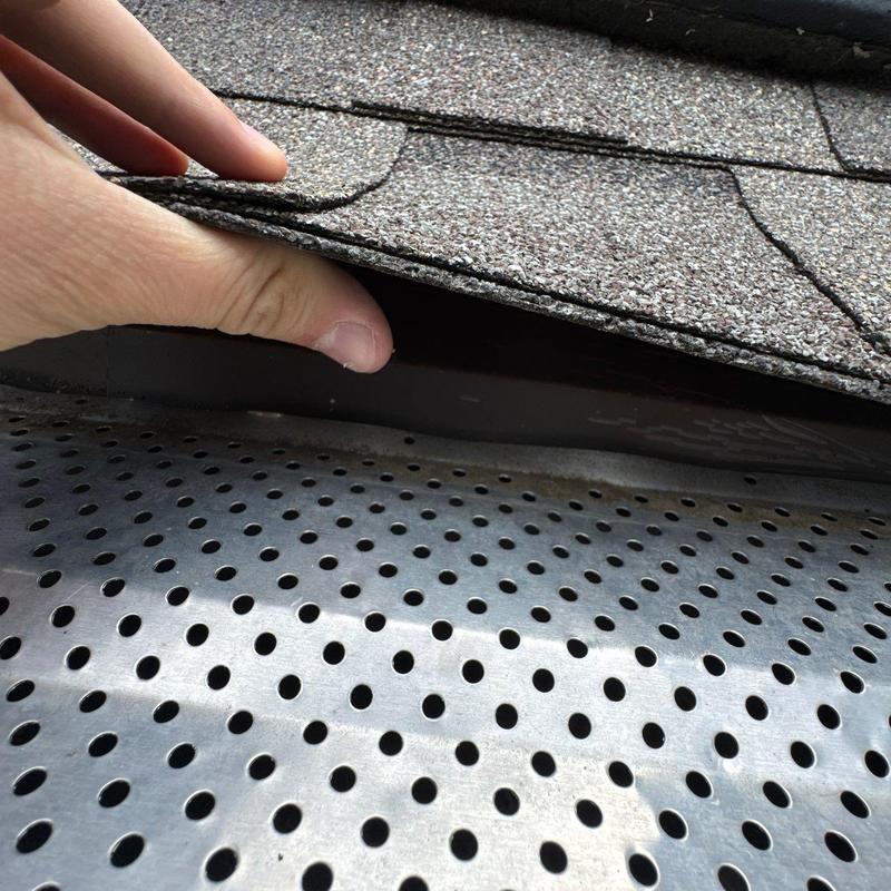 Asphalt shingles lifted revealing metal drip edge installation