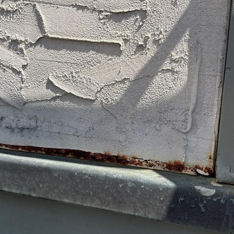 Metal flashing with rust and stucco wall damage