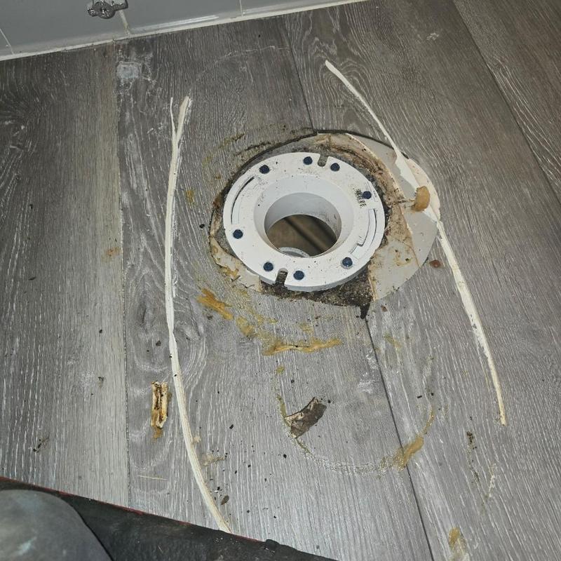 Toilet flange on wood-look floor with sealant residue
