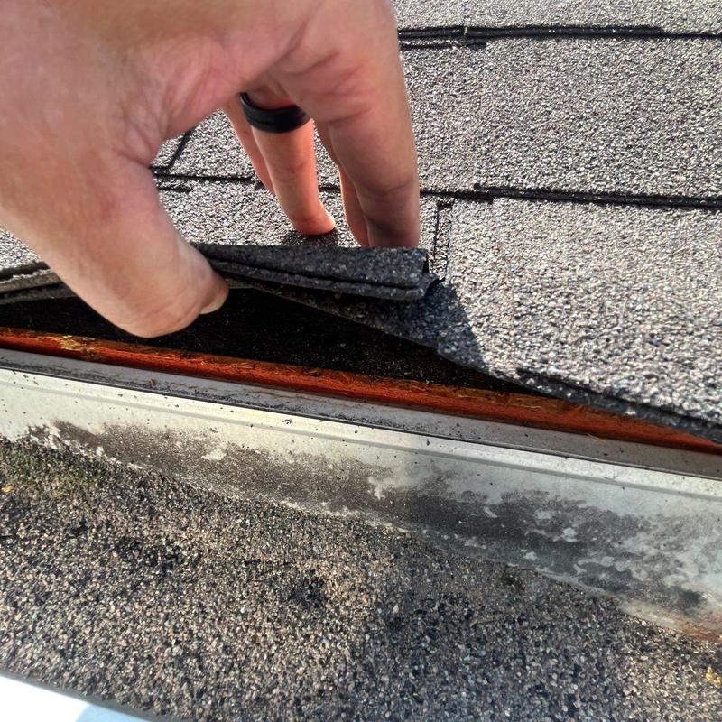 Asphalt shingles lifted showing hail damage on roof edge