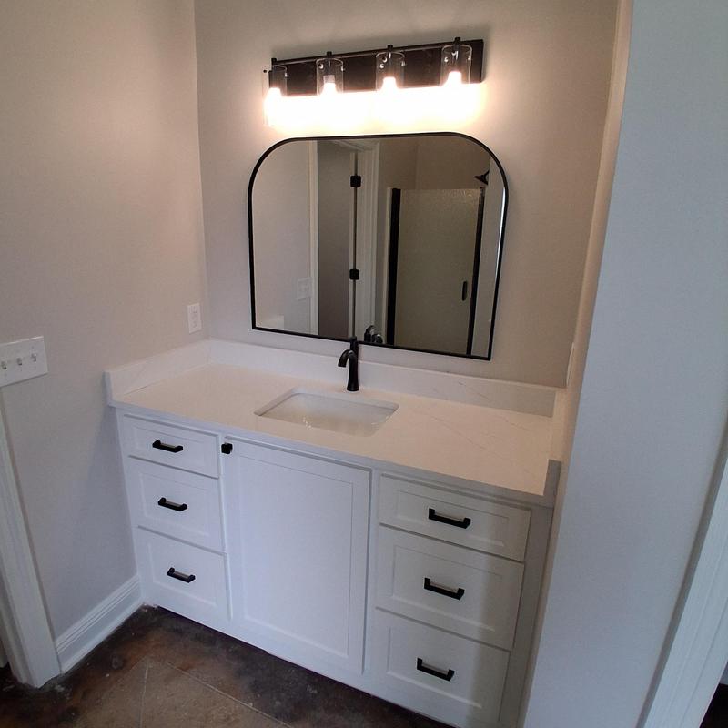 Bathroom vanity with mounted arched mirror and lighting