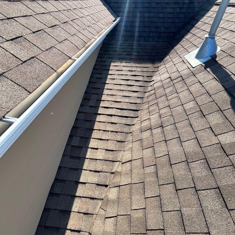 Asphalt shingle roof valley with hail damage signs