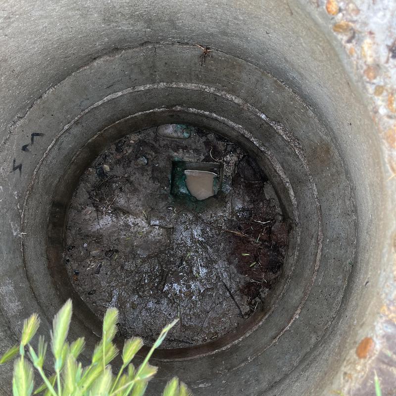 Storm drain clogged with mud and roots inside concrete chamber