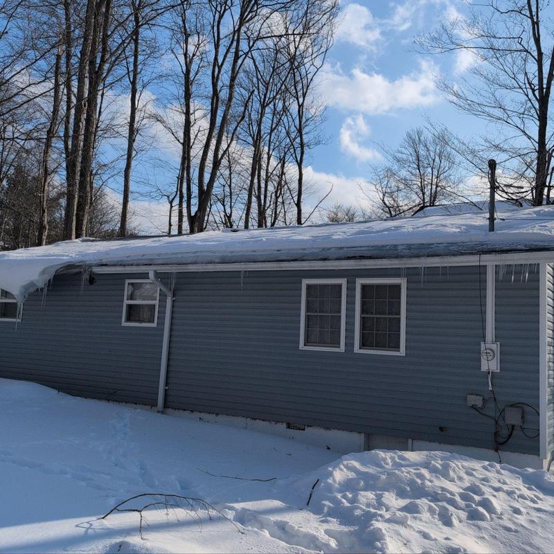 Residential roof with snow and icicles in winter Residential roof with snow and icicles in winter