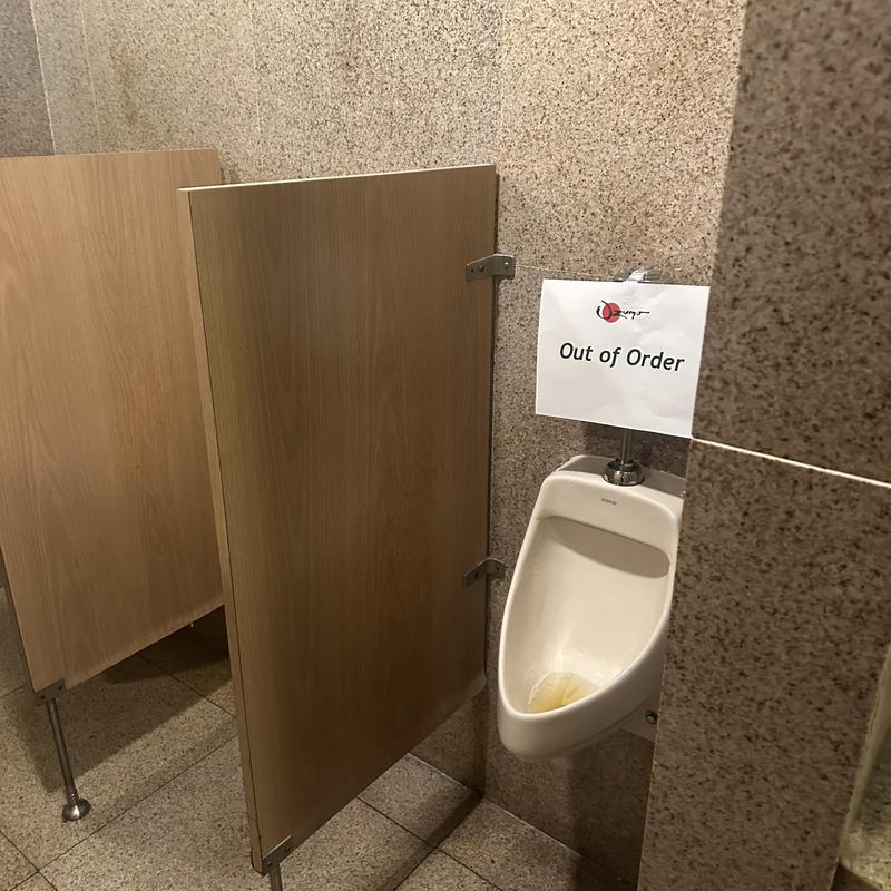 Sloan flushometer valve on urinal with out of order sign Sloan flushometer valve on urinal with out of order sign