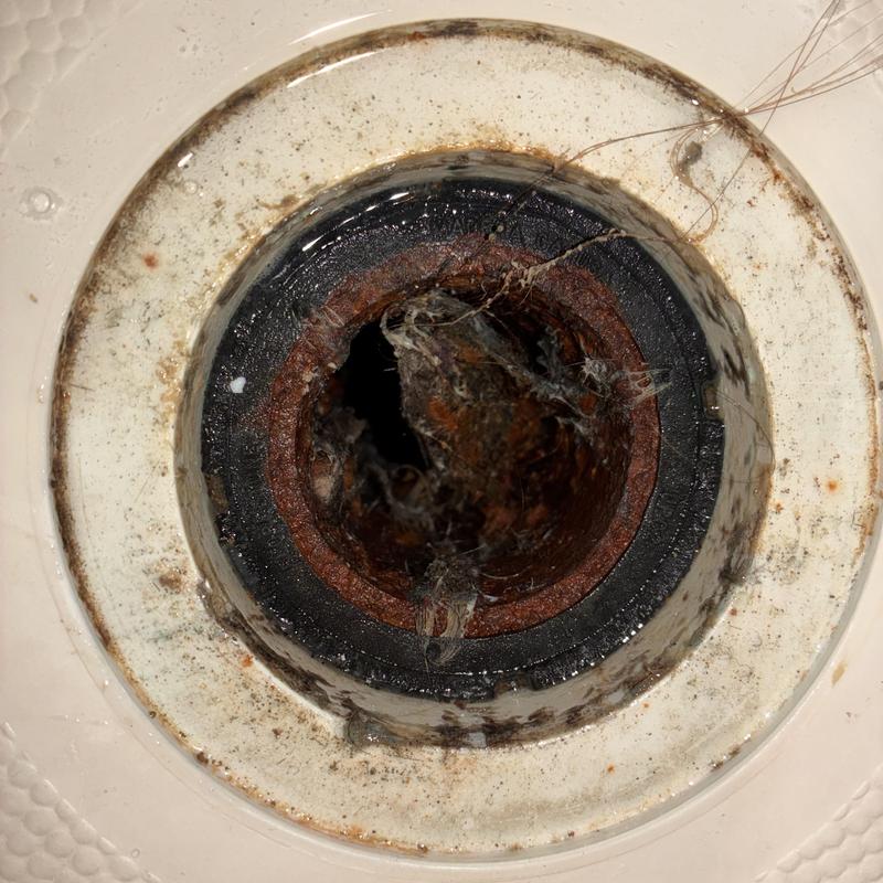 Shower drain clogged with rust and hair buildup