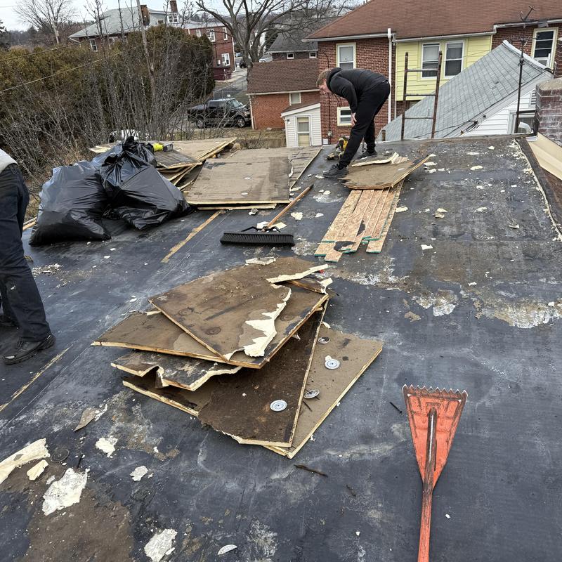 EPDM roof tear-off with debris and tools on rooftop
