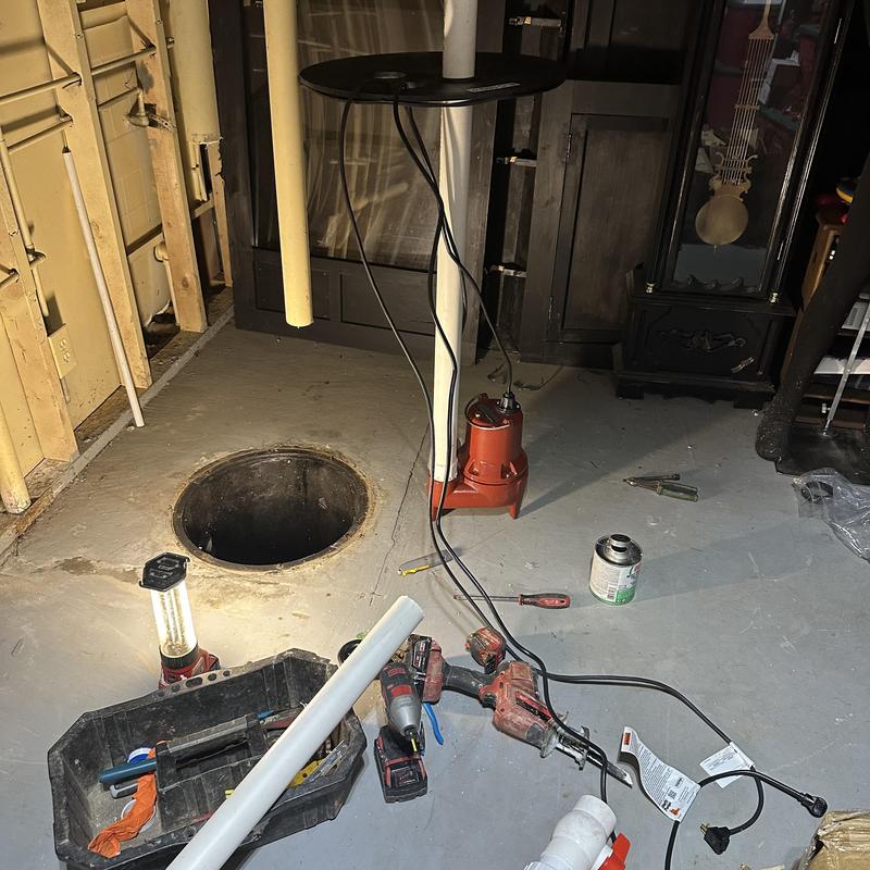Sewer ejector pump with tools and piping in basement