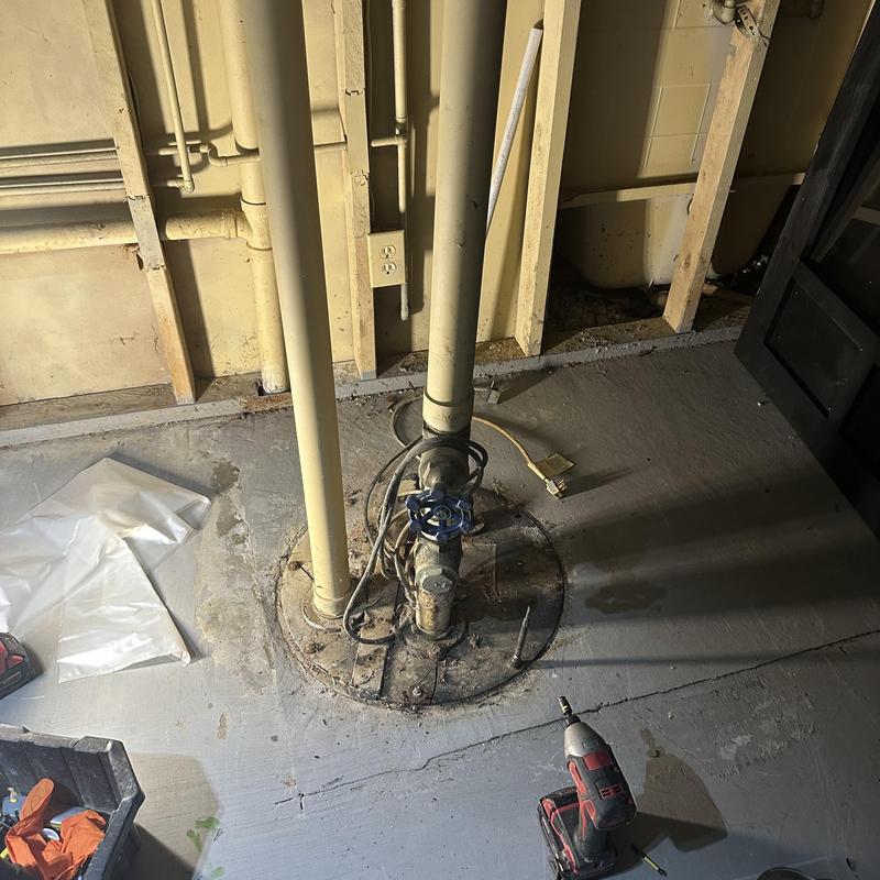 Sewer ejector pump with valve and tools in basement