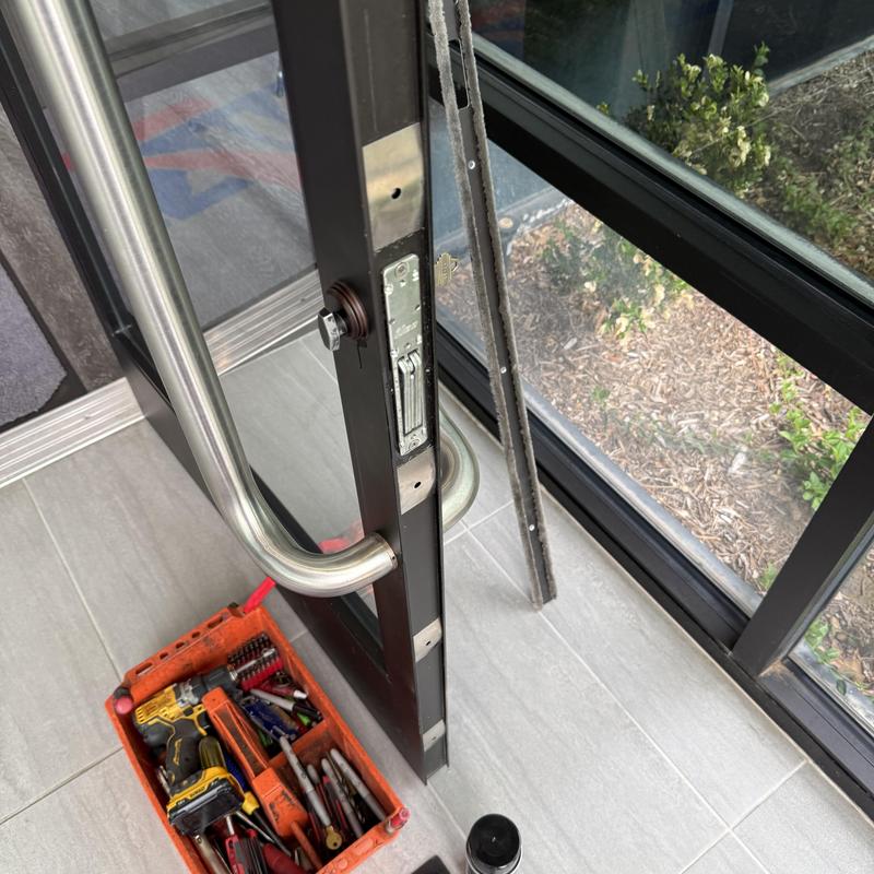 Mortise cylinder lock on commercial glass door with tools