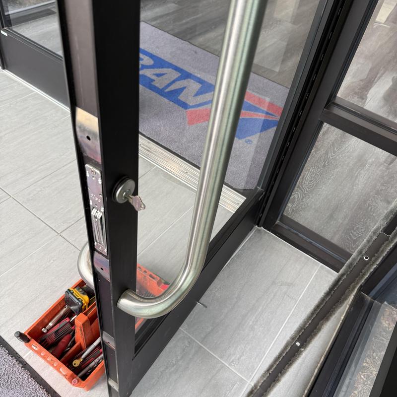 Mortise cylinder lock on commercial glass door with tools