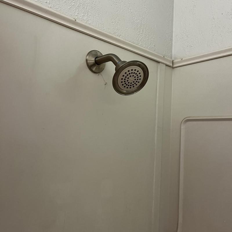 Showerhead and arm installed on tiled shower wall