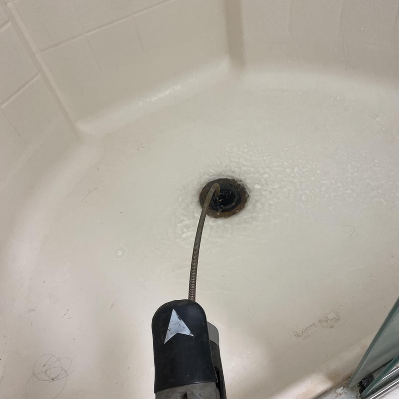 Shower drain clog clearing with sewer snake tool