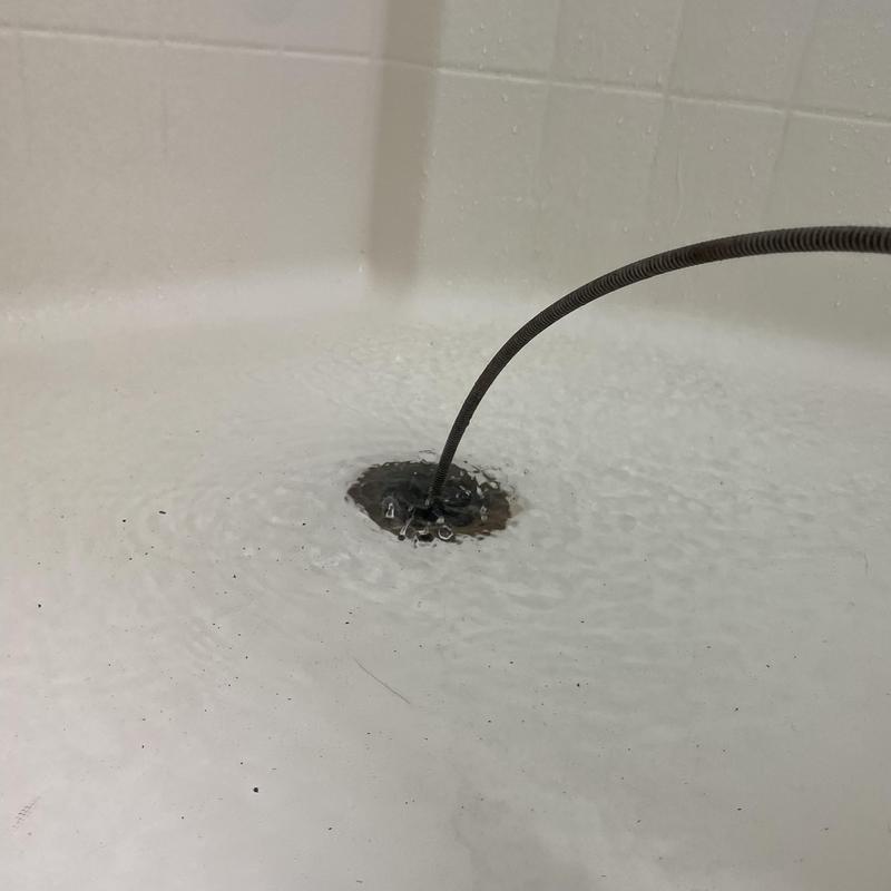 Shower drain clog clearing with sewer snake tool
