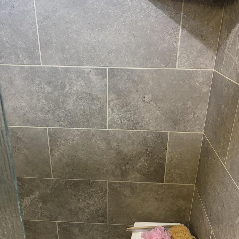 Walk-in tub corner with gray wall tiles and sponge