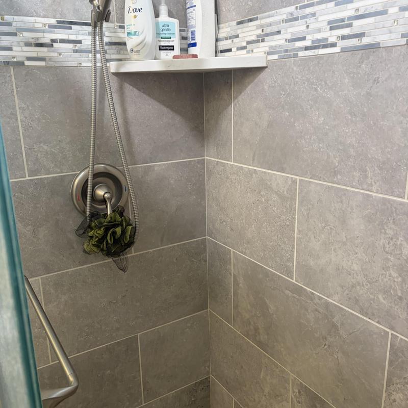 Shower valve and handheld showerhead in tiled shower corner