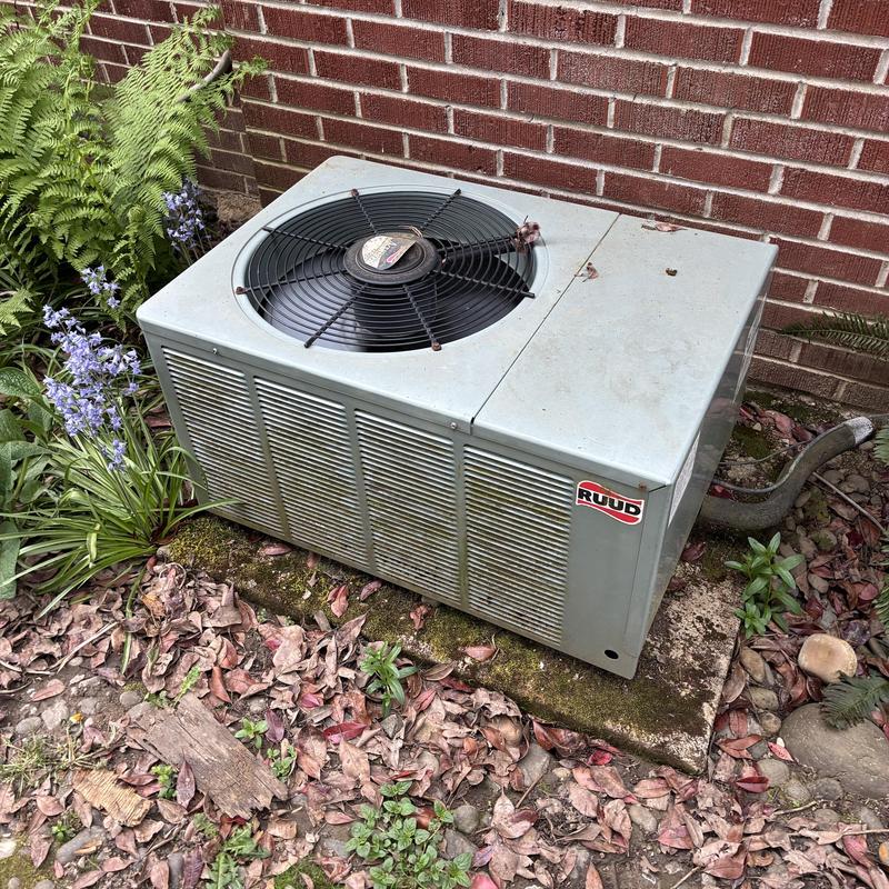 Outdoor Ruud air conditioner unit beside brick wall Outdoor Ruud air conditioner unit beside brick wall