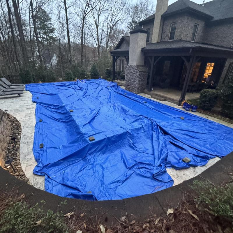 Swimming pool covered with blue tarp on patio