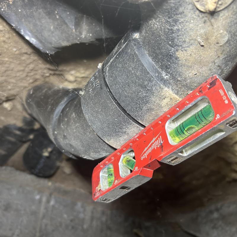 Building drain pipe with level tool checking grade