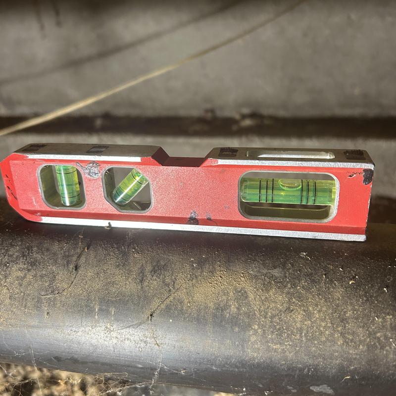 Building drain pipe level check with a red spirit level