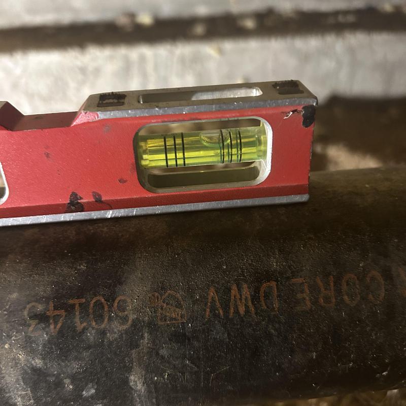 Building drain pipe level check with spirit level tool