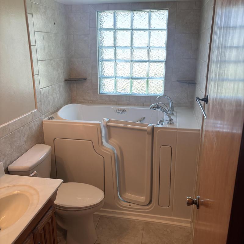 Walk-in bathtub with door and faucet in bathroom