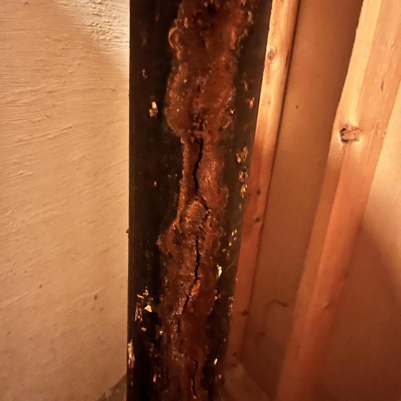 Corroded plumbing stack pipe in preschool building wall