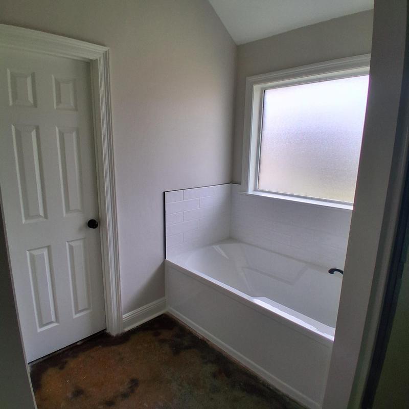 Bathroom bathtub with tiled surround and frosted window
