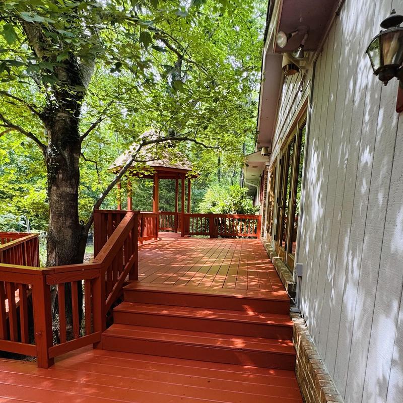 Wooden deck with gazebo and stairs in shaded yard