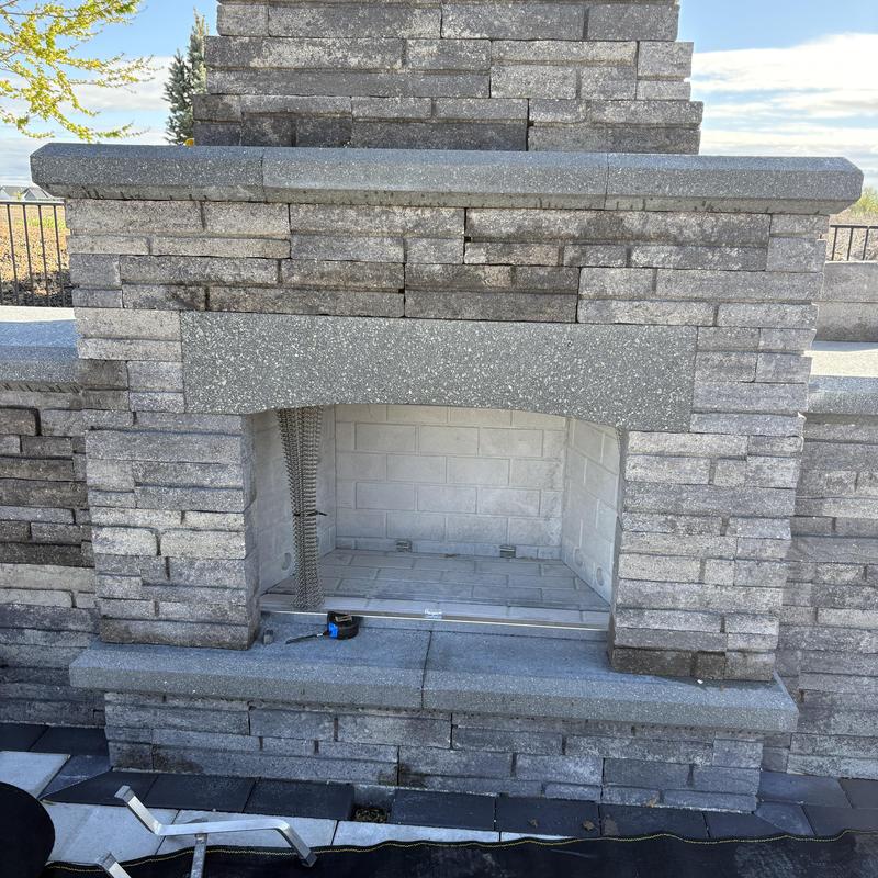 Outdoor stone fireplace insert opening with tools nearby
