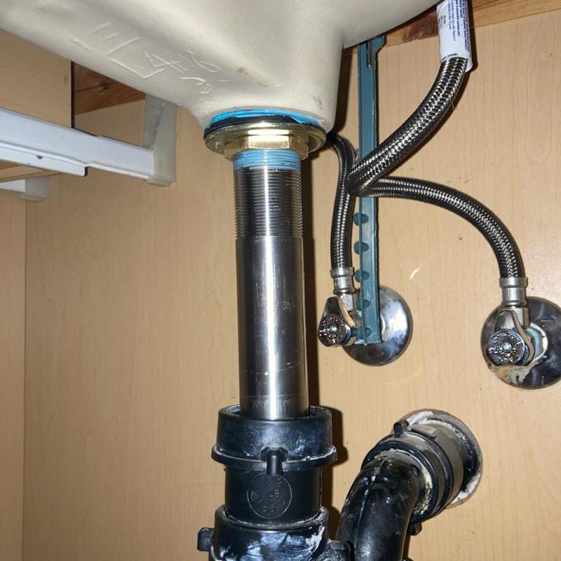 Sink drain pipe and water supply lines under bathroom sink.