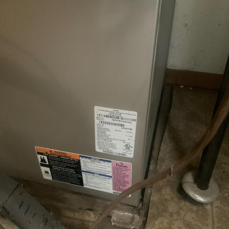 HVAC unit with safety and warning labels in basement corner