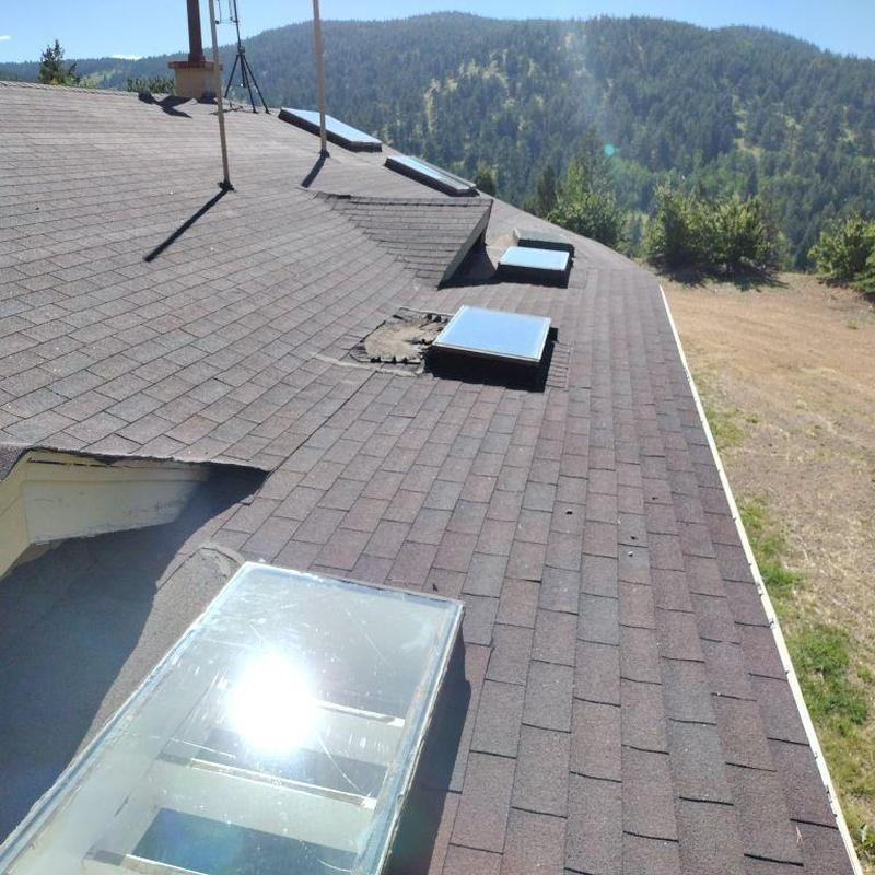 Shingle roof with damaged skylight and hail impact marks Shingle roof with damaged skylight and hail impact marks