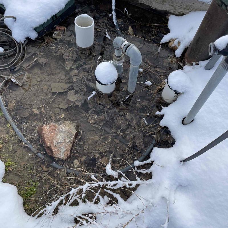 Irrigation valve and pipes in flooded snow-covered ground