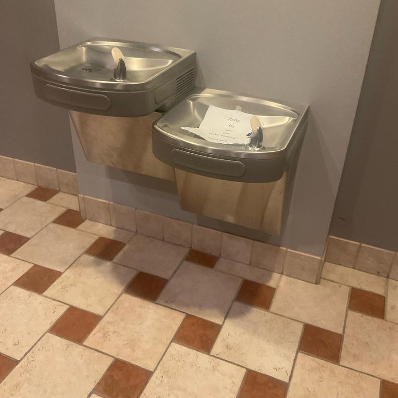 Drinking fountain with maintenance sign on tiled floor
