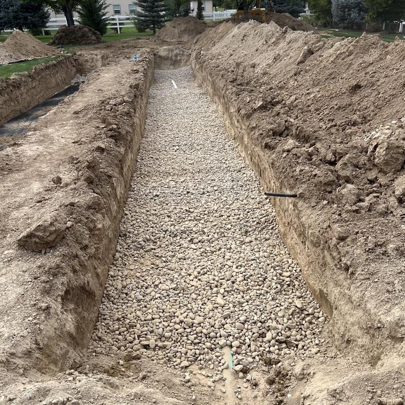 Drain field installation with gravel base in trench
