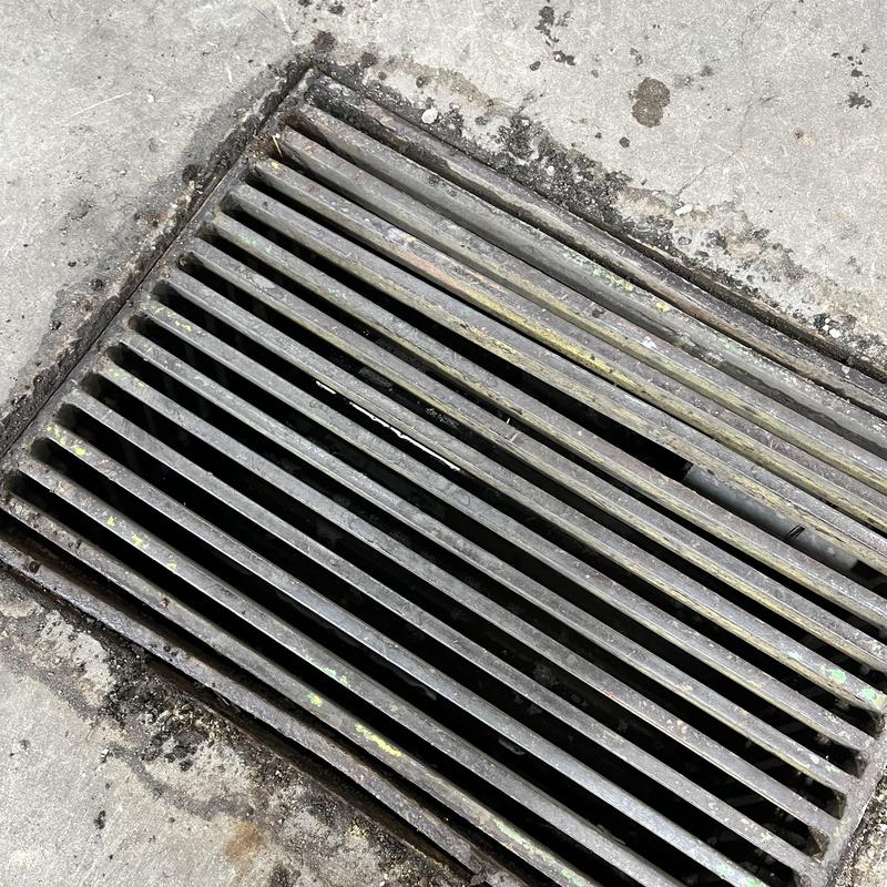 Truck wash bay drain with sediment buildup on concrete