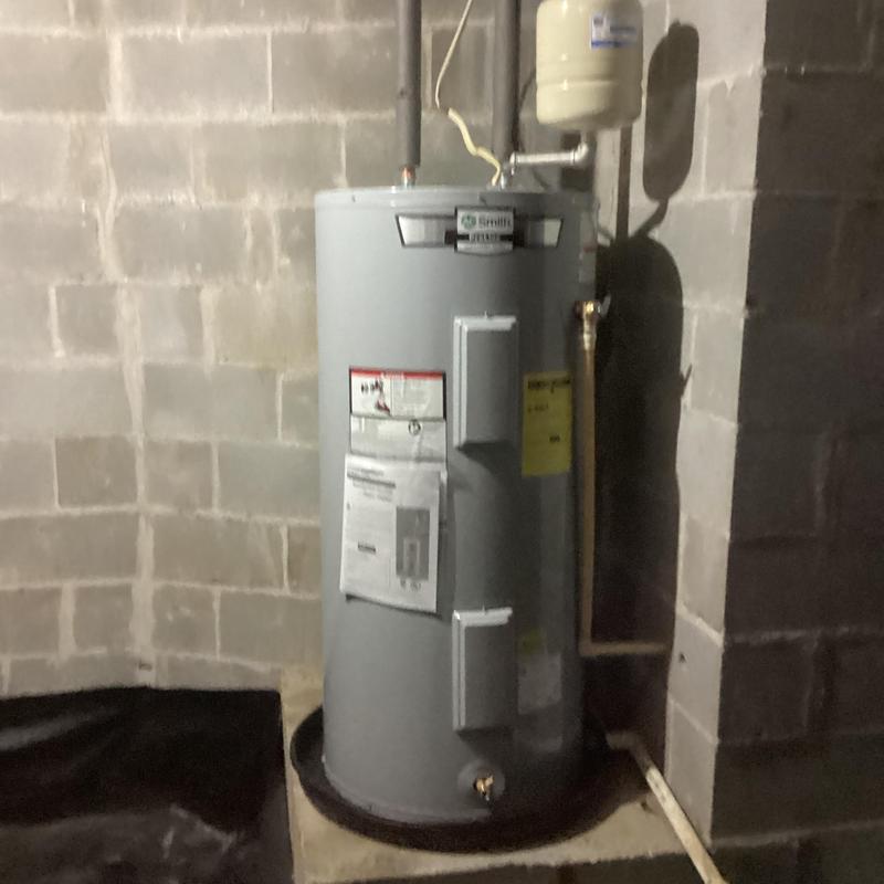 Electric water heater with copper pipe repair in basement